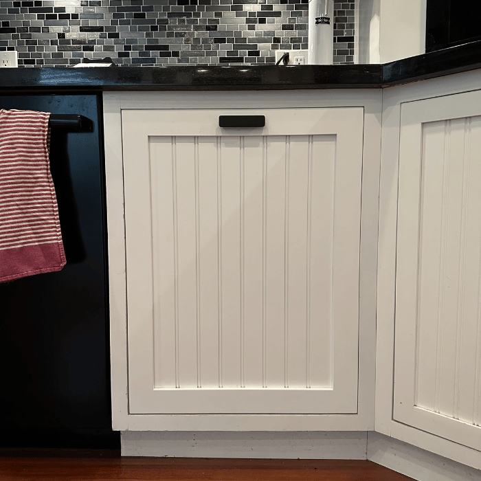 White beadboard cabinet door, elegantly accented with a sleek black cabinet pull